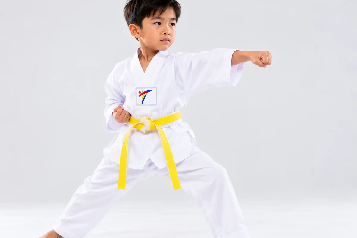 A young student in a white dobok and yellow belt holding a front-punch stance
